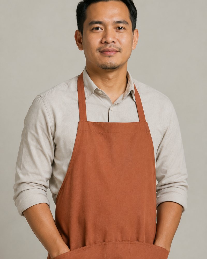 Hafiz Rahim dalam apron terakota dan kemeja linen di depan latar kelabu suam